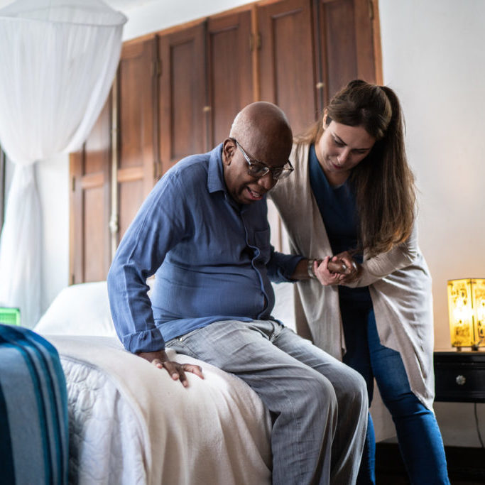 a person helping a person sit on a bed