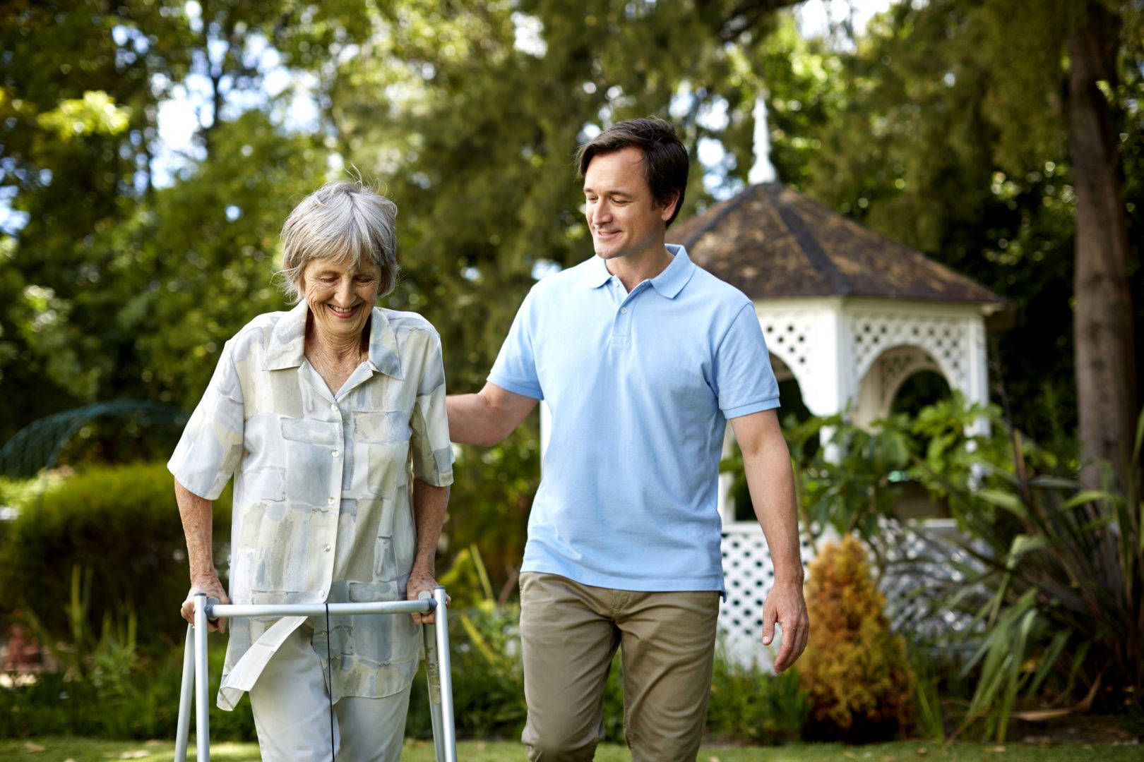 Adult son assisting mom with walker at nearby park