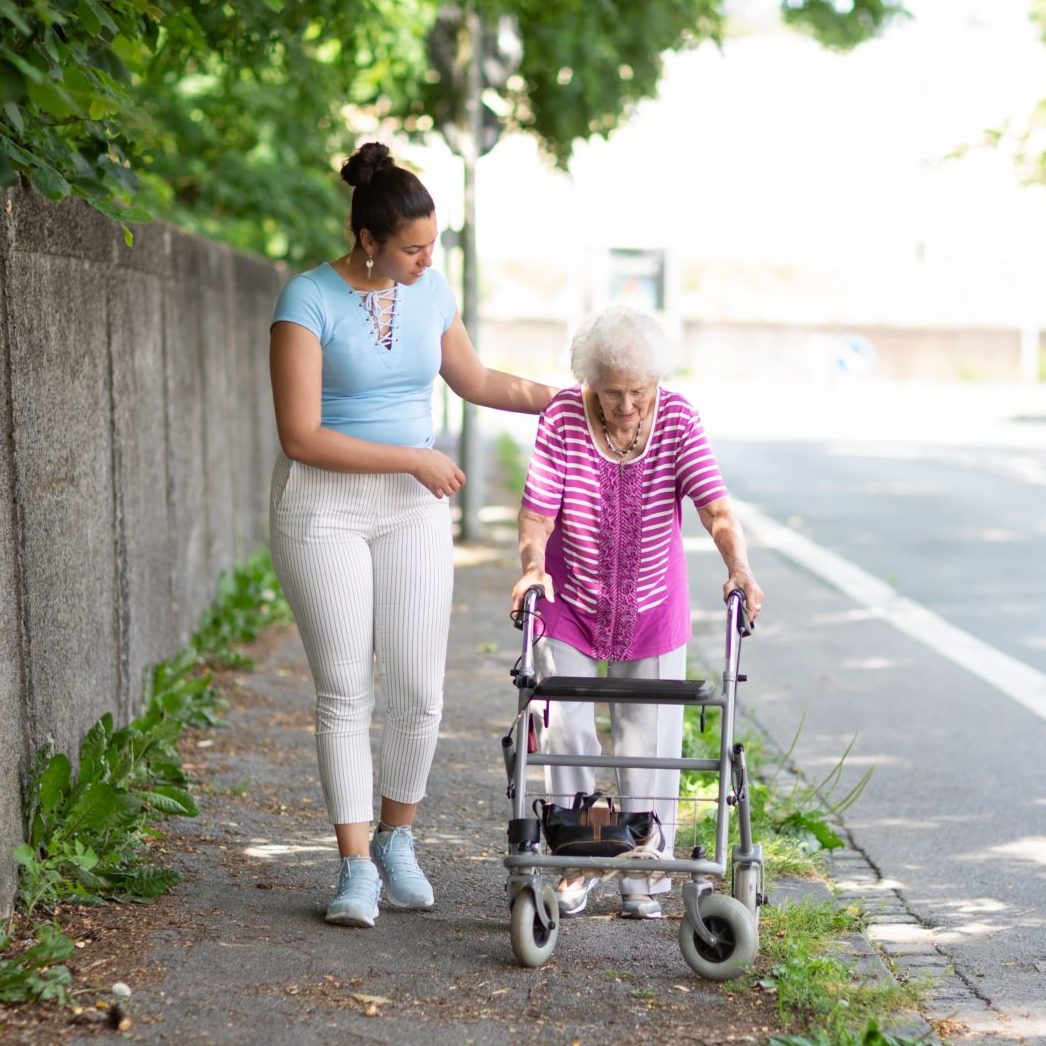 a person pushing an old person in a walker