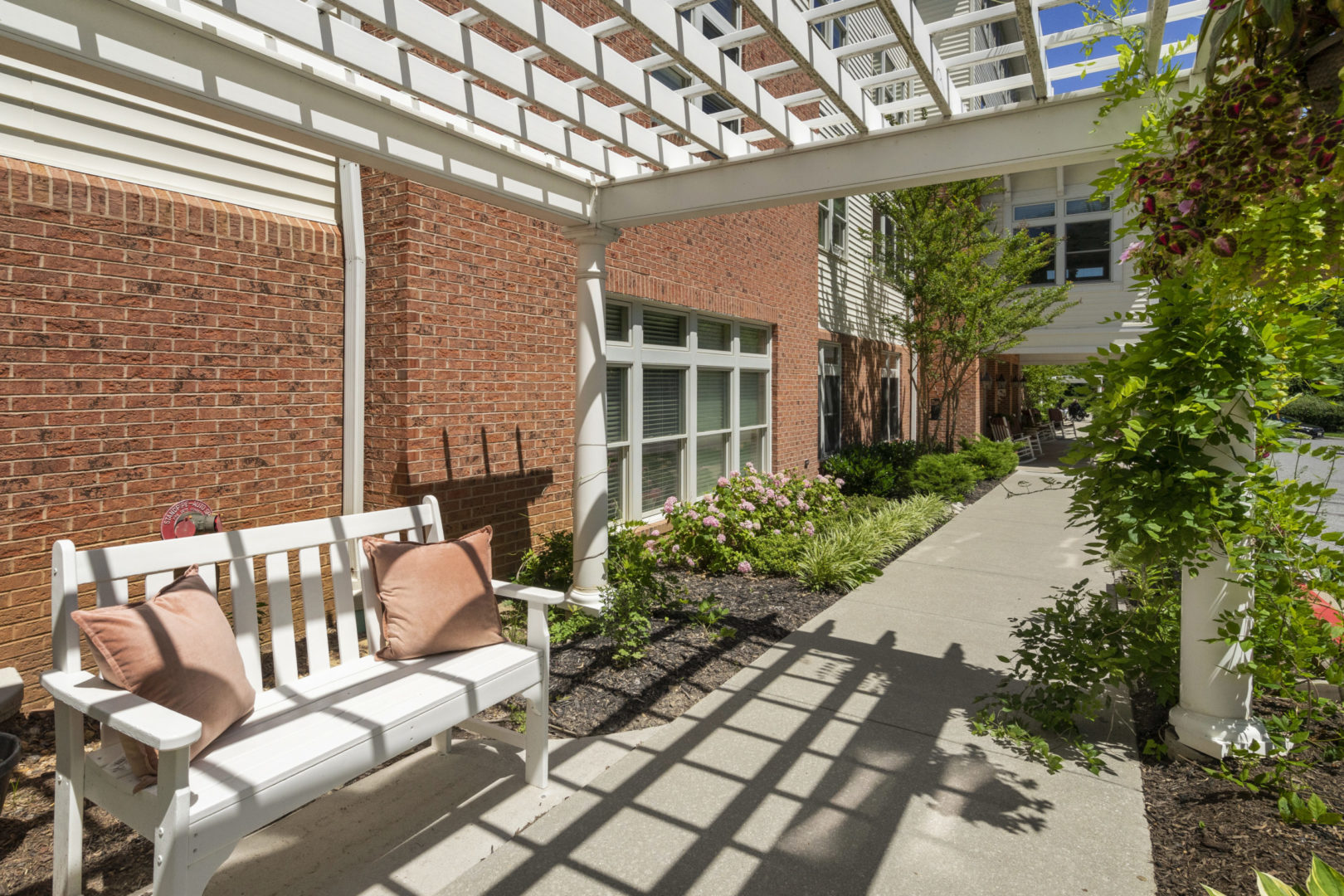 a white bench with pillows on it next to a brick building